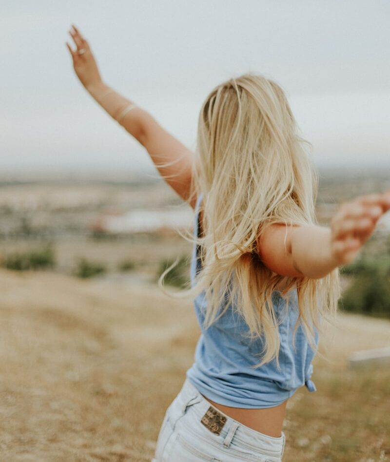 woman wearing blue top while standing on plain field