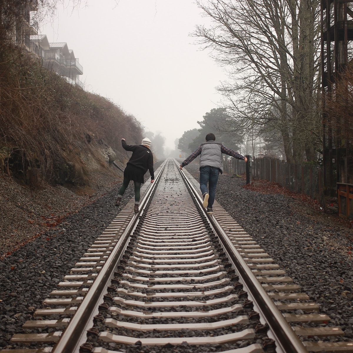 two person walking on the train rail