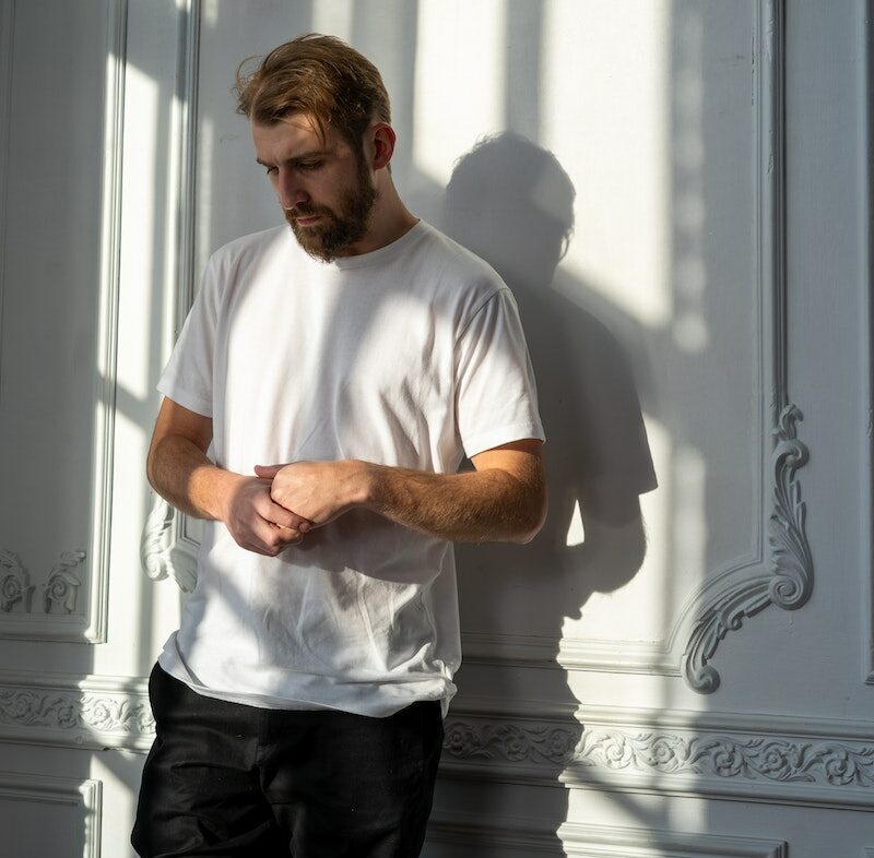 Man in White Crew Neck T-shirt Standing Beside Window